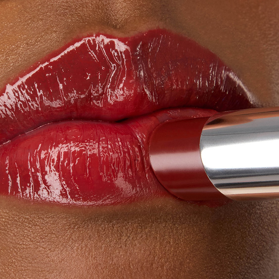 Nahaufnahme des YSL LOVESHINE Lippenstifts im Farbton 219 Berry Crush, der auf die glänzenden, leuchtend roten Lippen von Model Zahara aufgetragen wird.