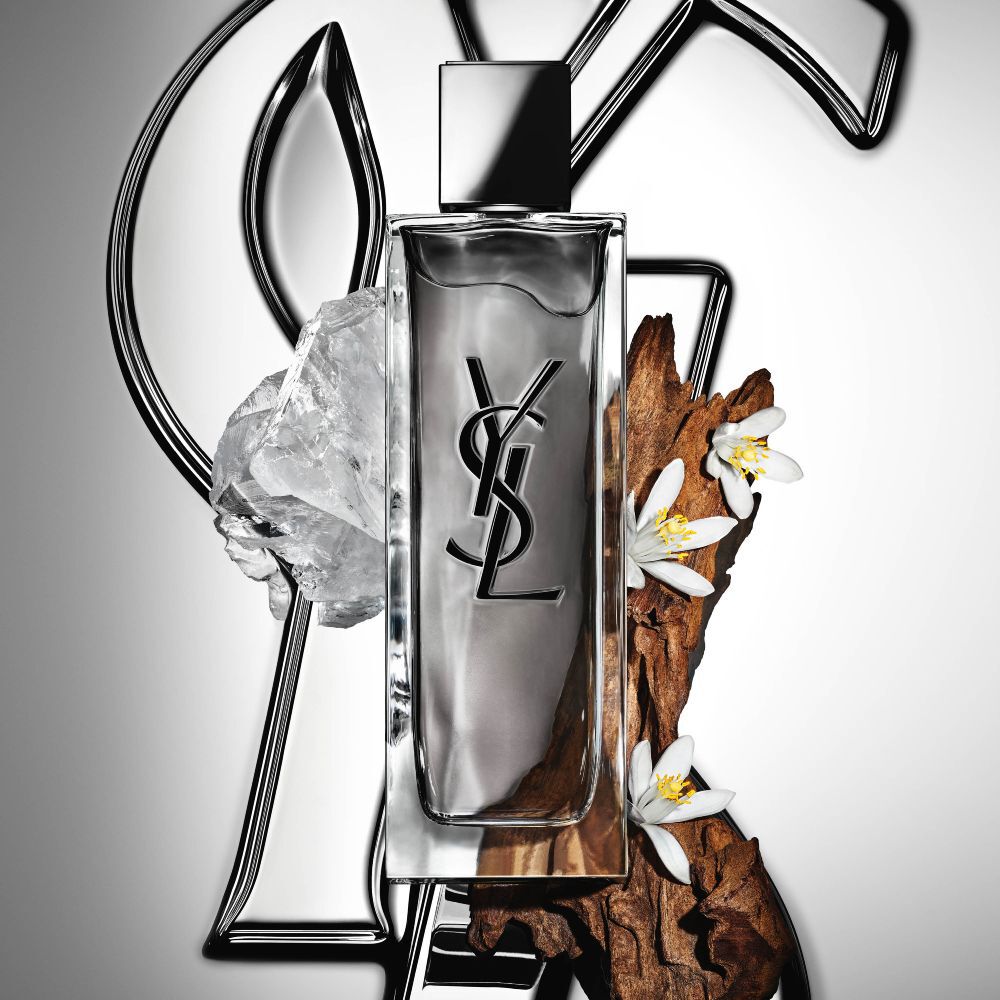 Der Flakon von MYSLF Eau de Toilette Intense von YSL Beauty, umgeben von Orangenblüte, Hölzern und weißem Moschus.